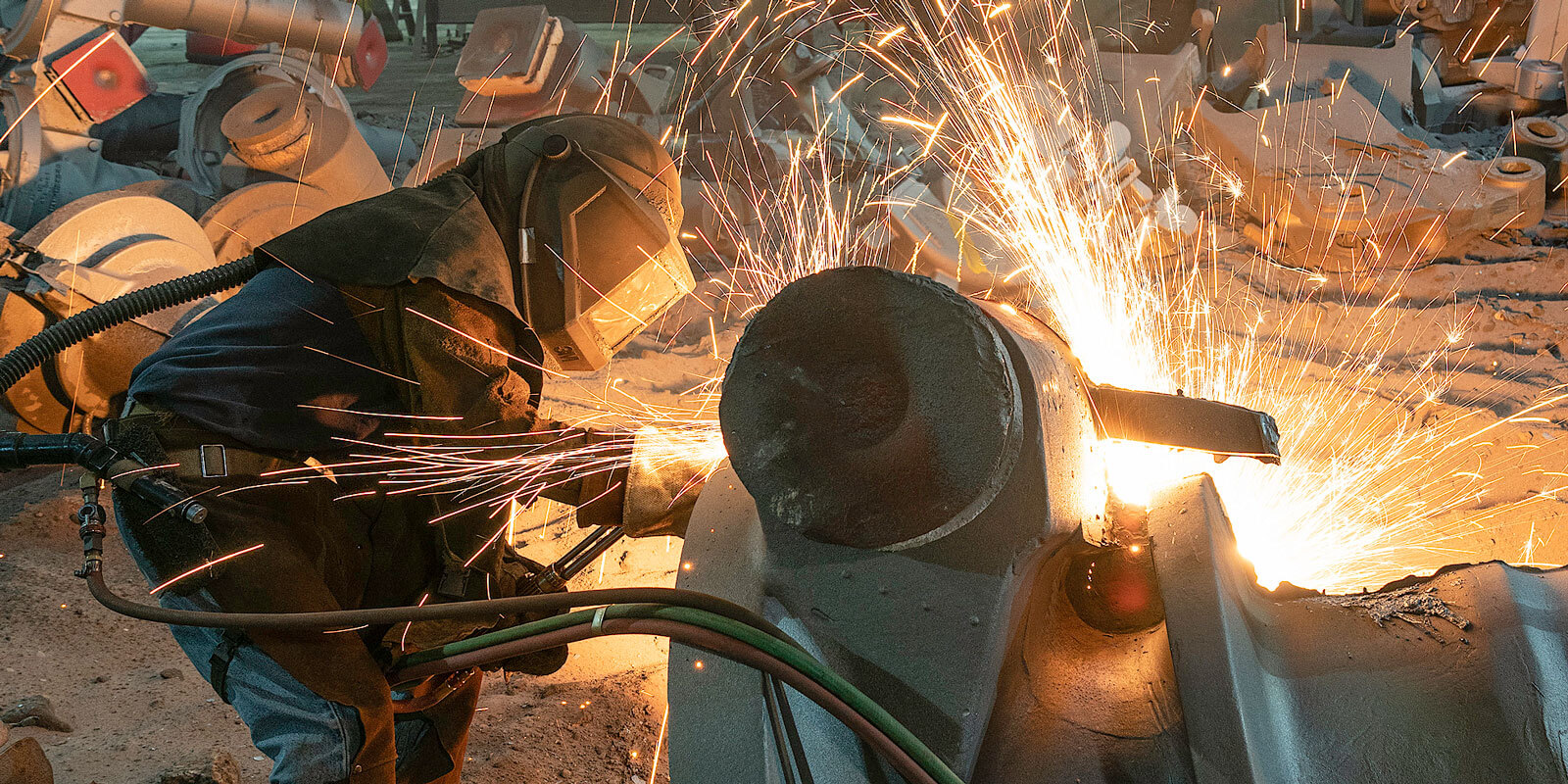 Worker using welding tools in steel foundry